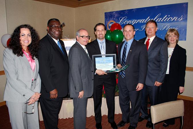 Pictured with MIA Hero of the Year Award winner Mohamed Badenjki (center) are, from left: Miami-Dade Assistant Aviation Director of Operations Lauren Stover; Miami-Dade Fire Rescue Airport Division Chief Levi Thomas; Miami-Dade Aviation Director José Abreu; American Airlines Customer Service Director Jim Moses; Miami-Dade Police Department Airport Division Major Daniel Llano-Montes; and Miami-Dade Aviation Division Director of Terminal Operations and Customer Service Dickie Davis.