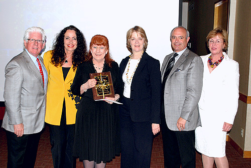 MIA Volunteer Ambassador of the Year winner Carol Dunstall (center) receives her award from: Greater Miami Convention and Visitors Bureau President and CEO Bill Talbert; MDAD Assistant Director of Operations Lauren Stover; MDAD Terminal Operations and Customer Service Division Director Dickie Davis; MDAD Director José Abreu; and MDAD Customer Service Supervisor Diana Berron.